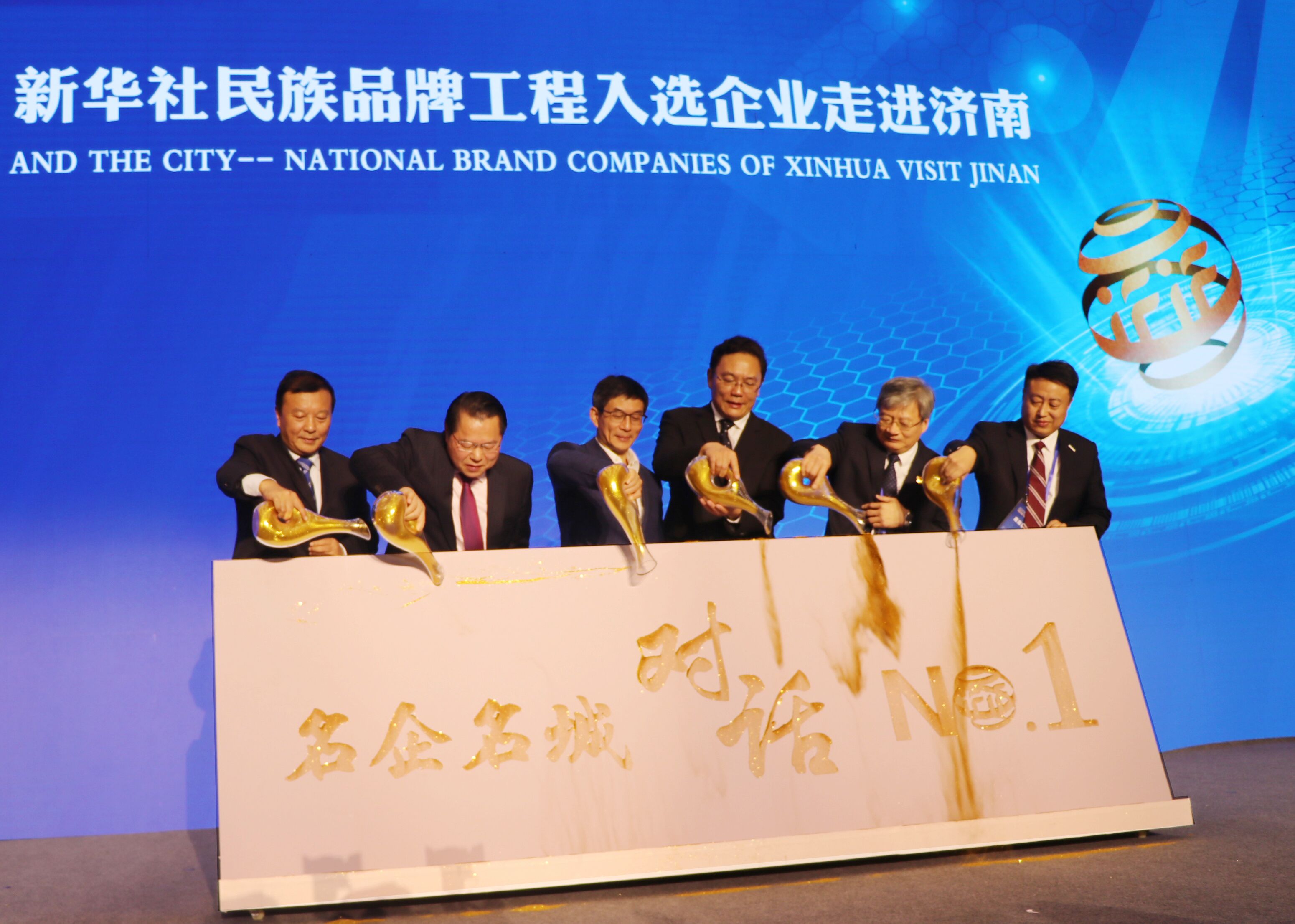 圖為新華通訊社副社長(cháng)兼秘書(shū)長(cháng)劉正榮（左三），濟南市委常委、副市長(cháng)，徐群（右三），全國政協(xié)委員、月星集團董事局主席丁佐宏（左二），全國人大代表，江蘇今世緣酒業(yè)董事長(cháng)、總經(jīng)理周素明（左一），中國重汽集團副總裁宋其東（右二），浪潮集團副總裁盧文杰（右一）共同“澆金”，啟動(dòng)首期名企名城對話(huà)——新華社民族品牌工程入選企業(yè)走進(jìn)濟南儀式。